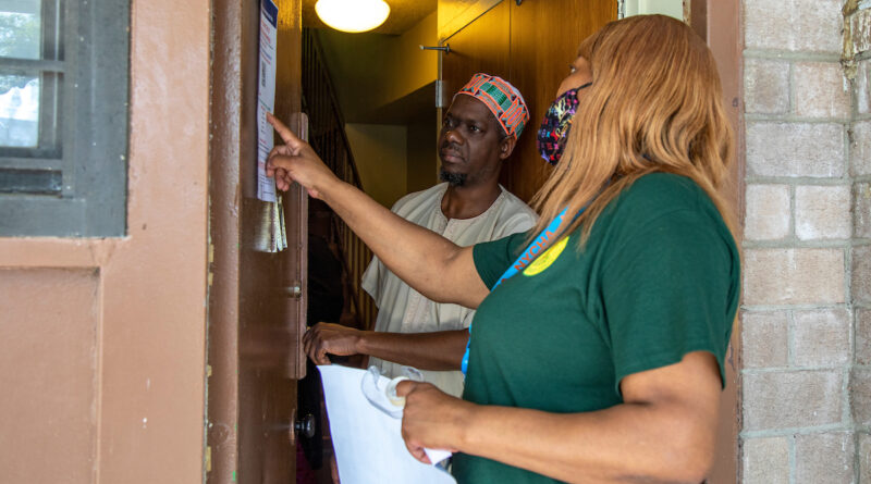woman in green shirt shows a man a flyer