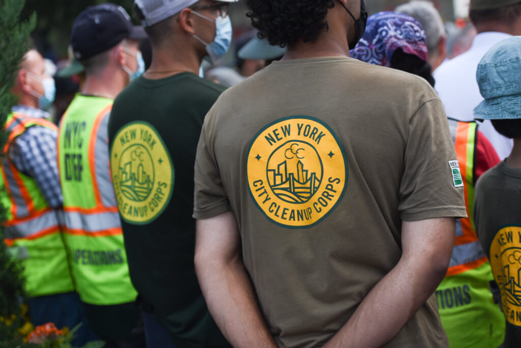 people with backs to camera wearing shirts that say City Cleanup Corps