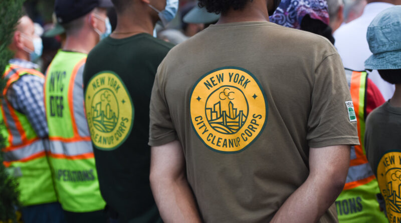 people with backs to camera wearing shirts that say City Cleanup Corps