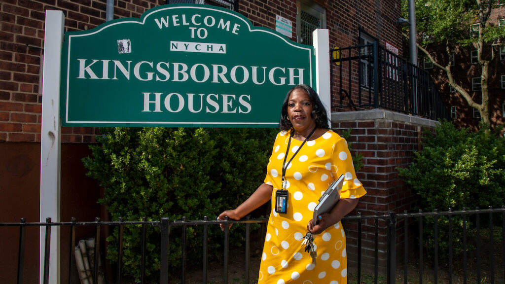 woman in yellow dress standing in front of outdoor sign for Kingsborough Houses