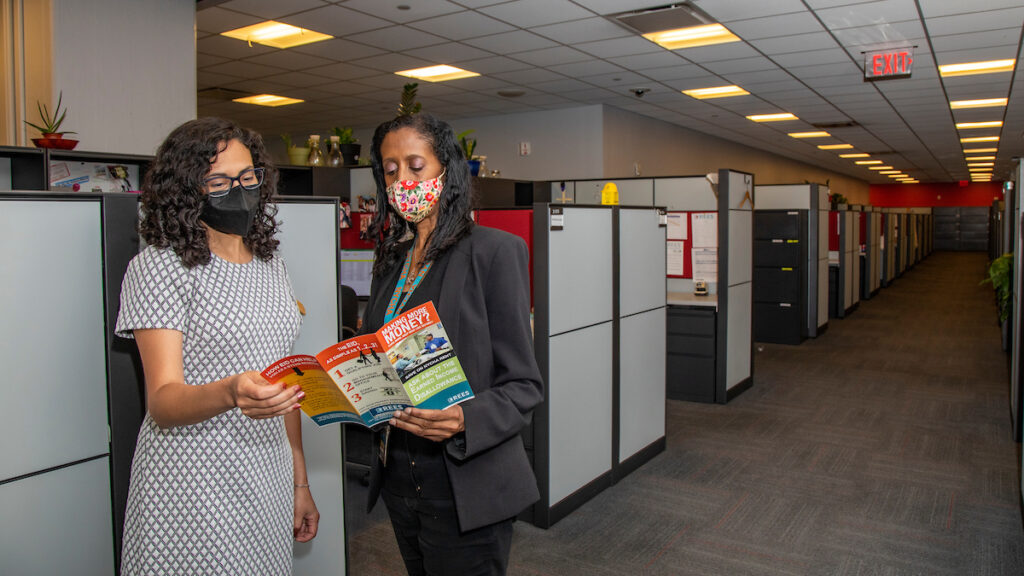 two women wearing face masks talking inside of an office building