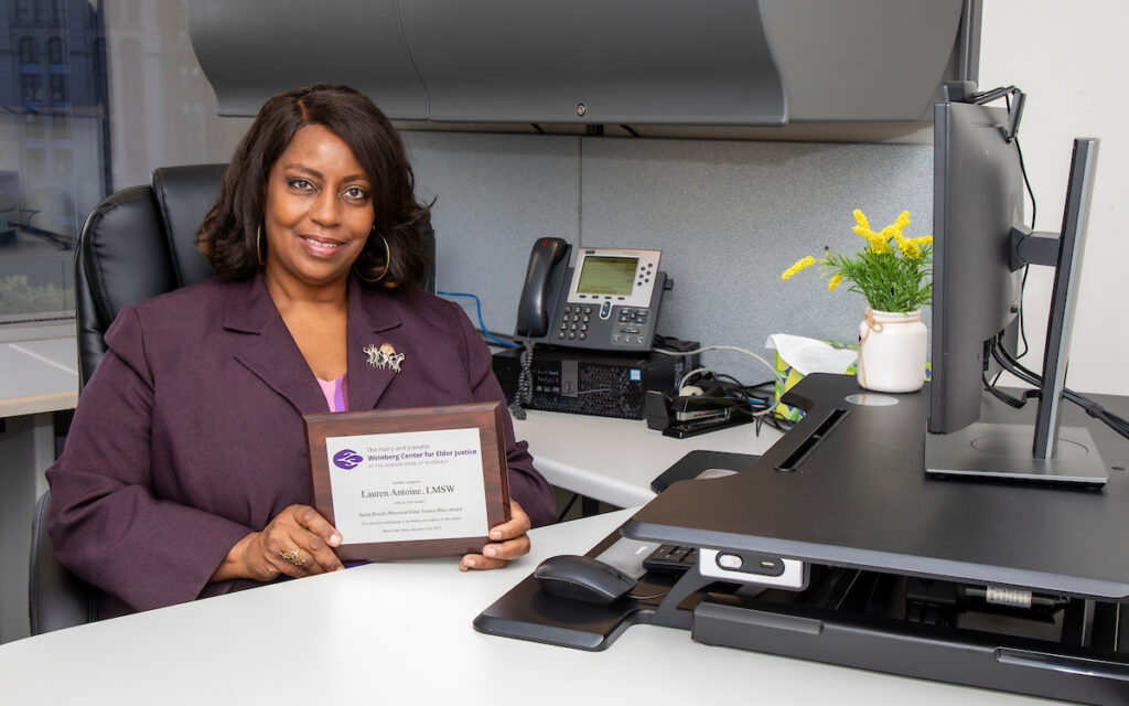 woman seated at desk holding a plaque