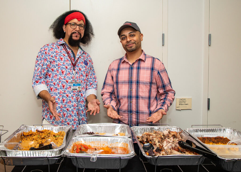 two men in front of trays of food