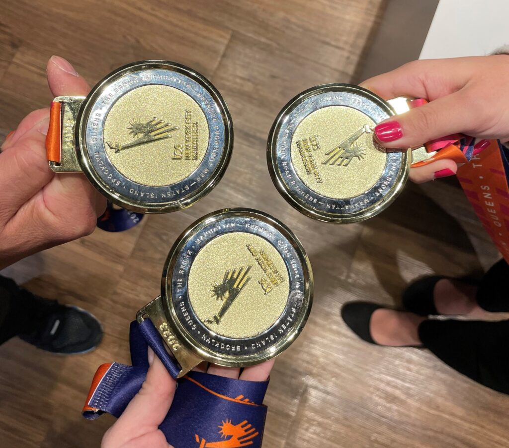 Image of three people holding out New York City Marathon Medals