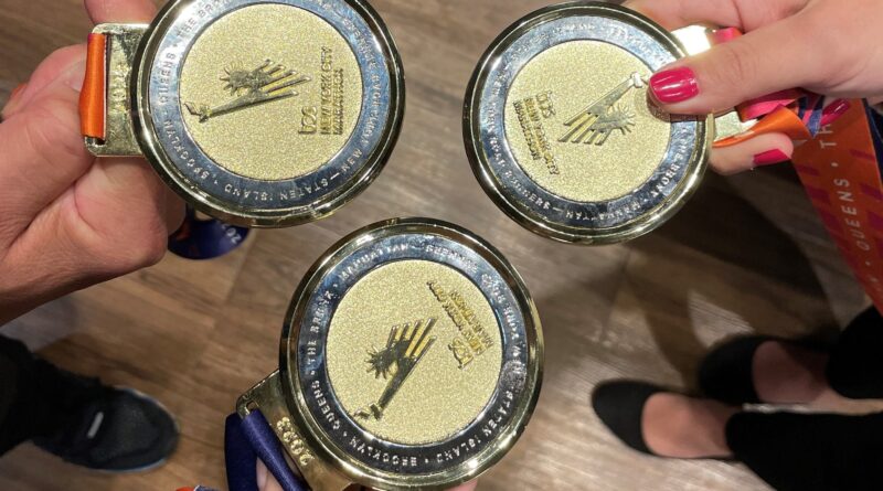 Image of three people holding out New York City Marathon Medals