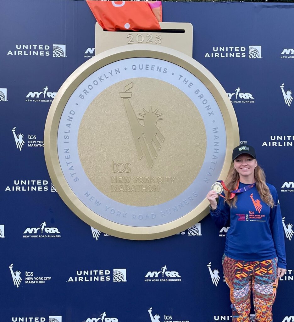 An image of a NYCHA employee posing with their medal after running the 2023 New York City Marathon.