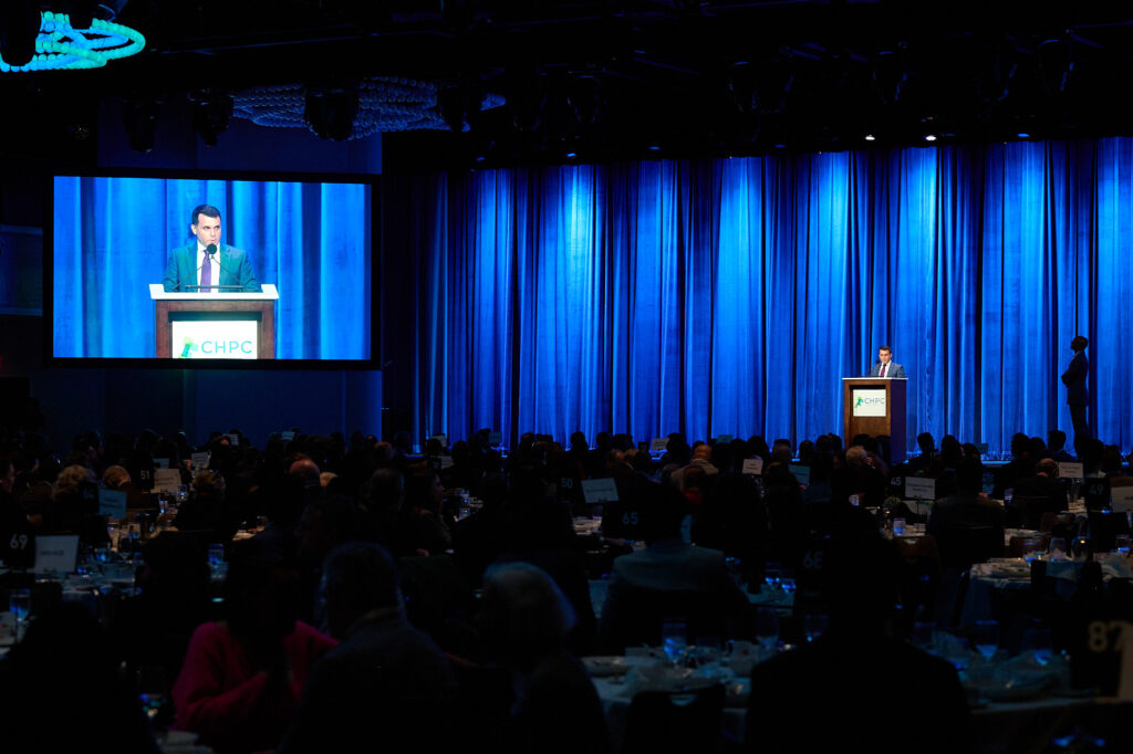 man standing at podium and pictured on a big screen