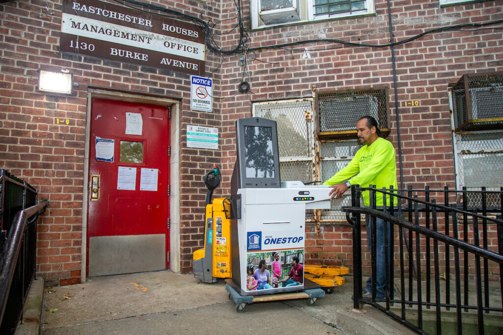 man wheeling a self-service kiosk into a building