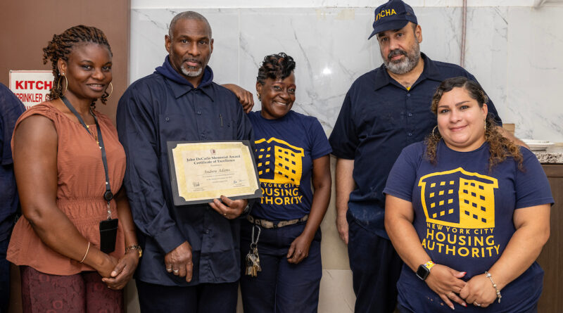 A group of five individuals, including one holding a certificate, stand together in a room with a “New York City Housing Authority” logo on their shirts.