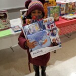 A child holds a toy received at a toy giveaway held by the Van Dyke Houses Resident Association on Christmas Eve.