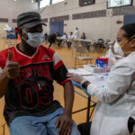 COVID-19 Vaccine Distribution at Van Dyke Houses Community Center. man receiving COVID-19 vaccine from a woman