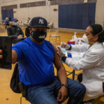 COVID-19 Vaccine Distribution at Van Dyke Houses Community Center. man taking selfie while receiving COVID-19 vaccine
